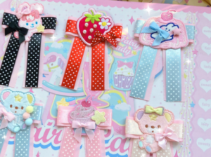 Assorted Sweet Lolita corsage hair clips featuring black polka dot ribbons pink bowknots cute animal and strawberry embroidery details on cartoon themed product display board