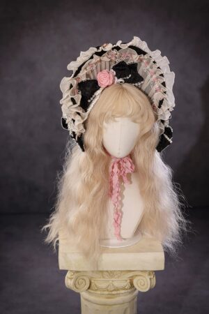 Vintage Rococo Lolita bonnet with ruffled black lace trim, pink fabric rose accent, and matching pink ribbon necktie displayed on wooden mannequin with blonde curly wig
