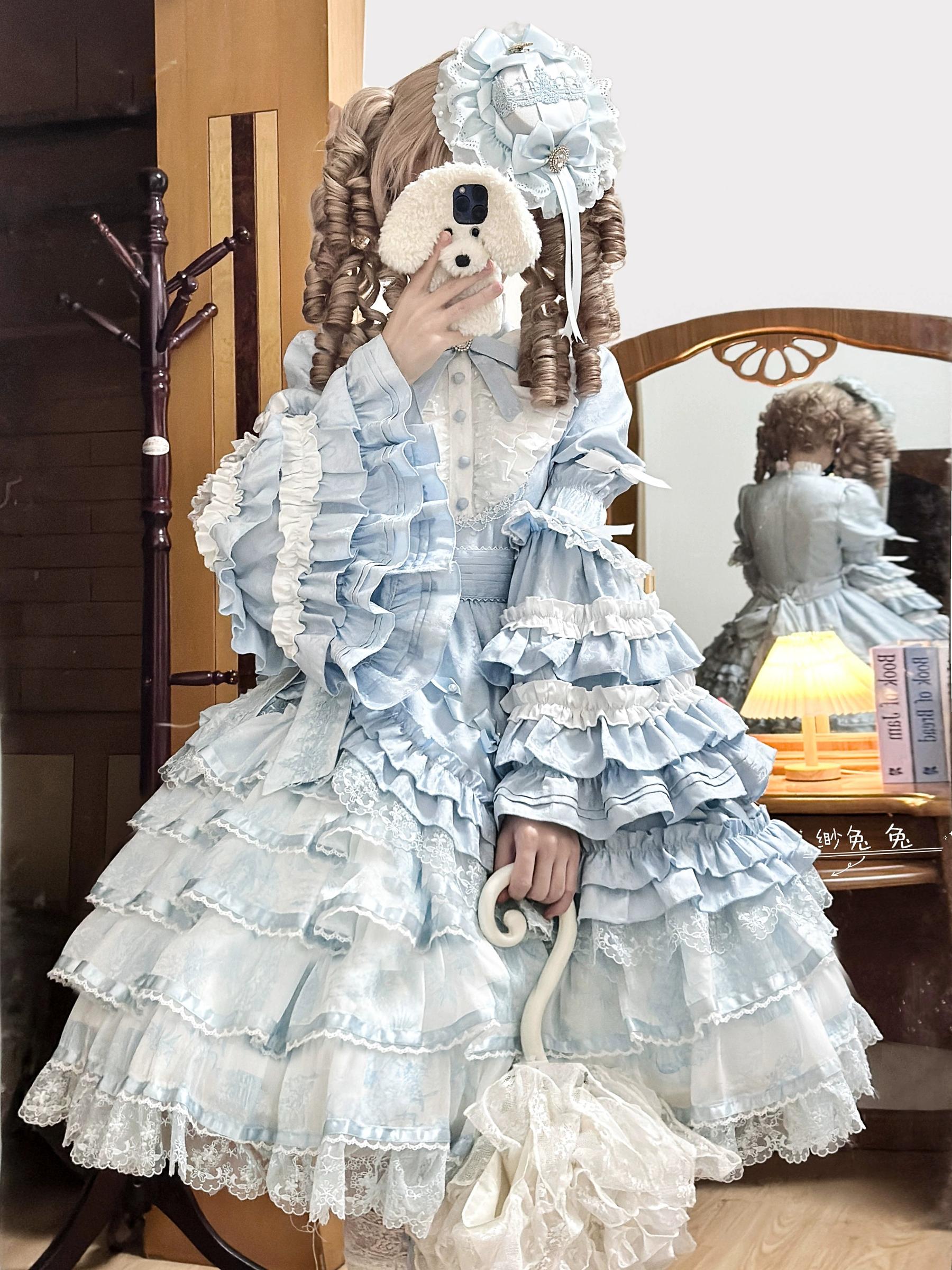 Solo Puppet sweet lolita OP dress sky blue color front three-quarter view with princess long sleeves multi-layered lace ruffles tiered skirt lace-trimmed stand collar flared A-line silhouette model wearing flower hair accessory