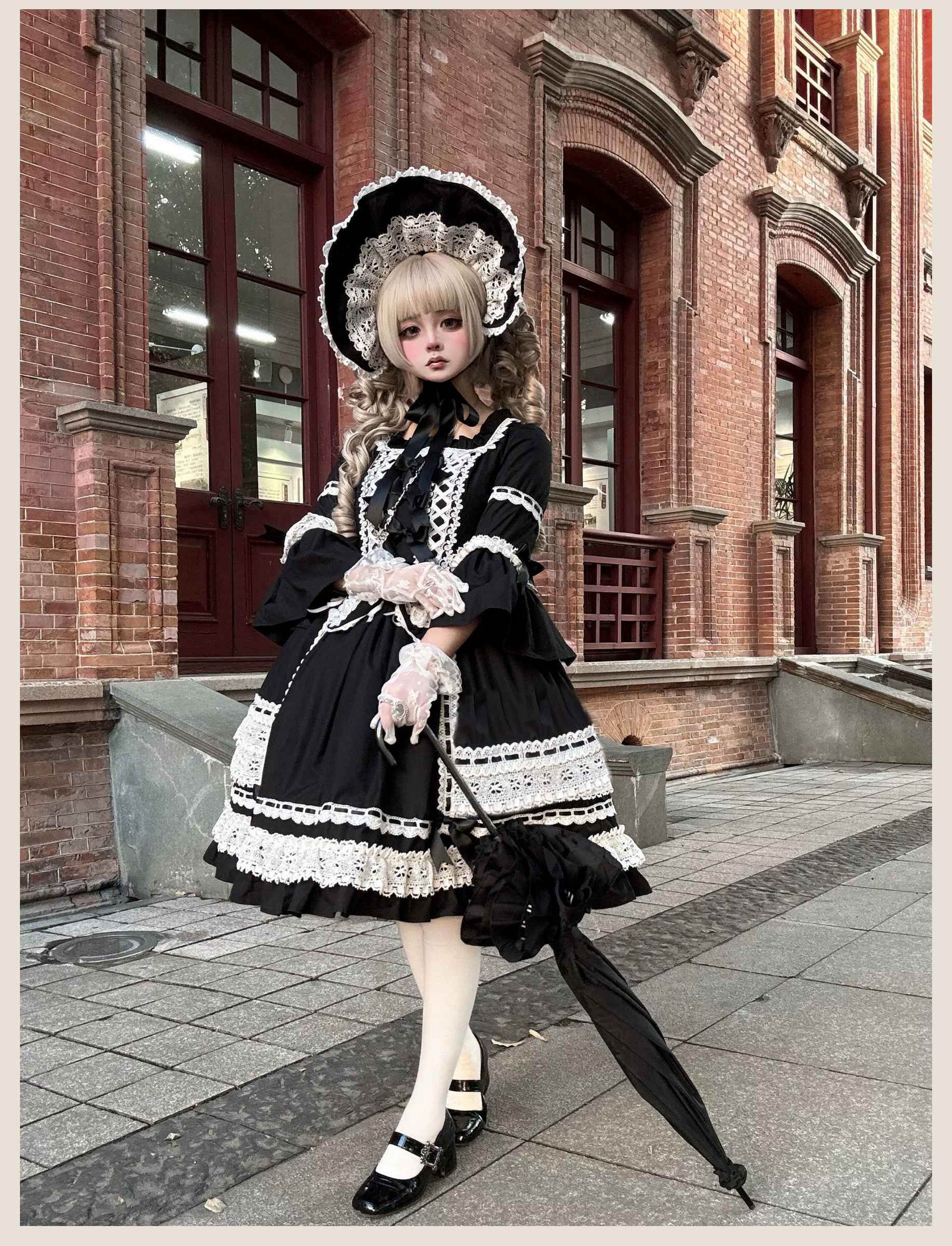 Full body side profile of black old school lolita one-piece dress showing A-line silhouette, layered skirt volume, matching bonnet, and vintage Victorian proportions