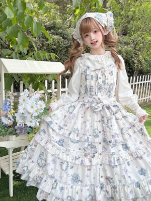 Meow Wreath Lolita JSK dress with matching inner blouse hair bonnet outdoor garden white fence floral ornaments full-body front view ruffled neckline waist bow multi-layered skirt