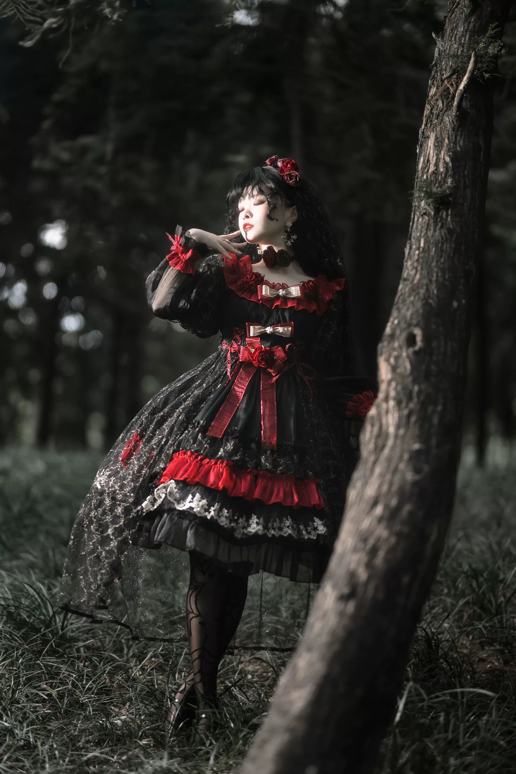 Night of Berea gothic lolita OP dress full-body side standing view in dark forest, displaying flowy silhouette with sheer black tulle skirt overlay and tiered design