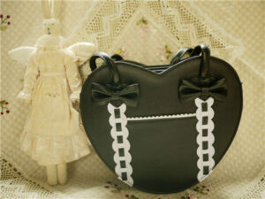 Full black heart-shaped Lolita tote bag with dual bow accents front view vintage lace background