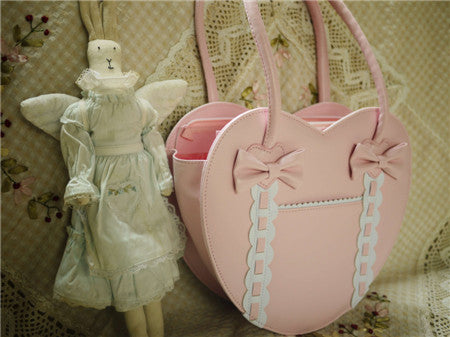 Light pastel pink heart-shaped Lolita tote bag three-quarter view with pink bows and white ruffled front pocket trim
