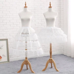 Two white hollowed-out lace lolita petticoats with delicate floral carving patterns displayed on wooden mannequin stands in studio setting