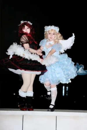 Angel and demon lolita coordinate comparison - blue celestial OP with white wings and red-black gothic lolita dress with ruffle lace details studio shot