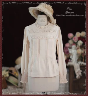 Apricot beige vintage Lolita long-sleeve cotton blouse with ruffled stand collar, front pin-tuck pleats, frilled wrist cuffs, and fabric bow tie displayed on dress mannequin with straw hat against retro floral studio backdrop