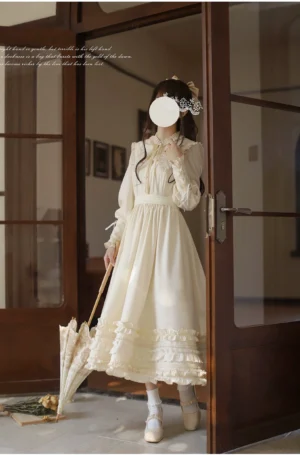 Cream apricot Lolita OP one-piece dress side profile view, showcasing mutton sleeves and layered ruffled skirt hem, worn with closed lace parasol at indoor doorway entryway