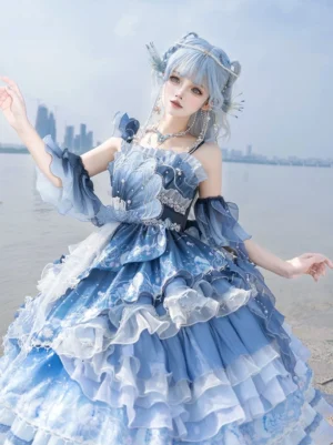 Azure Breath Jellyfish classic lolita jumper dress front three-quarter view worn on model at coastal beach showing ombre blue-white layered ruffled skirt and off-shoulder shell-shaped bodice design