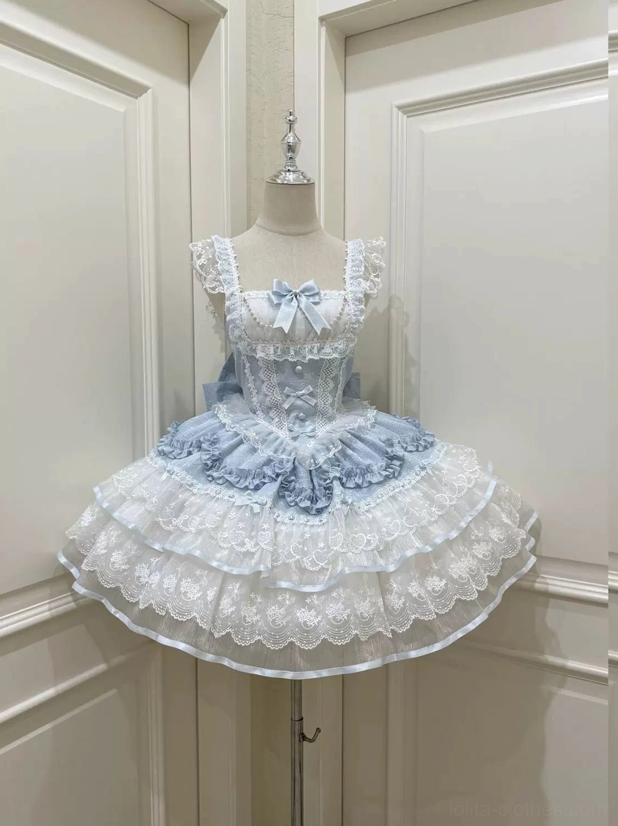 Front view of baby blue sweet lolita JSK dress featuring ruffled square neckline, delicate satin bow at bust, multi-layered lace ruffled petal-style skirt on dress form