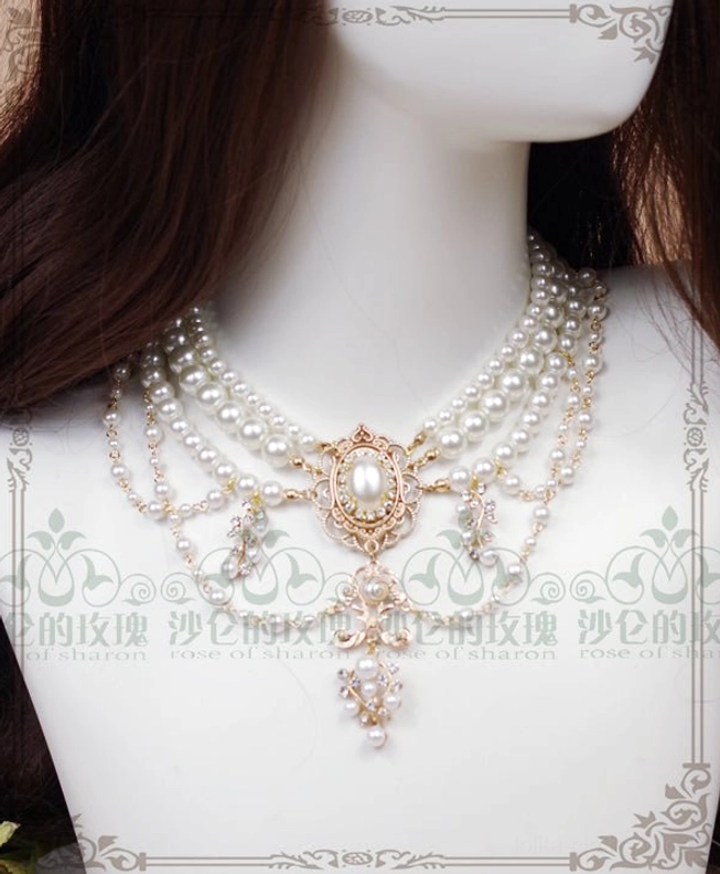 Close-up frontal detail of baroque pearl choker necklace on torso mannequin with brown wig showing delicate filigree refined central pendant