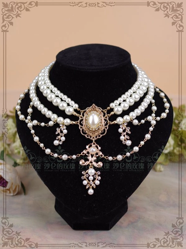 Baroque pearl layered choker necklace with white pearls and gold filigree front view displayed on black velvet mannequin with floral backdrop