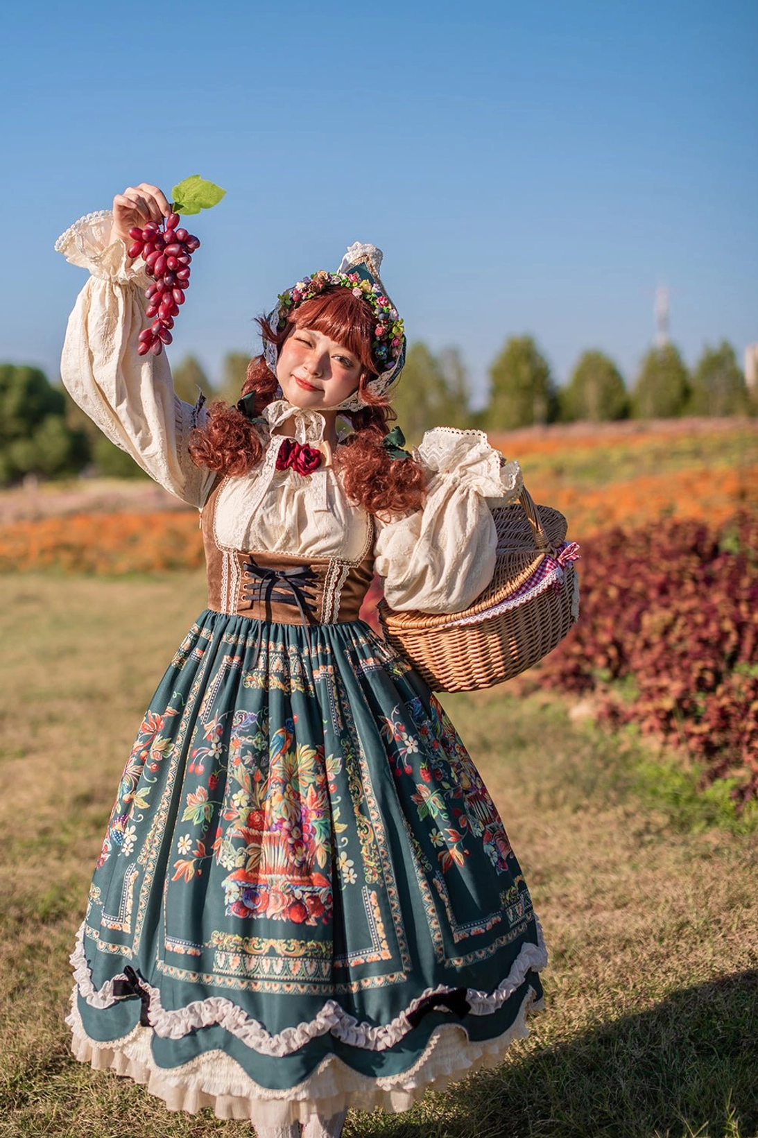 Bavarian Lolita JSK detail shot with red-haired model holding grape props in sunlit flower field