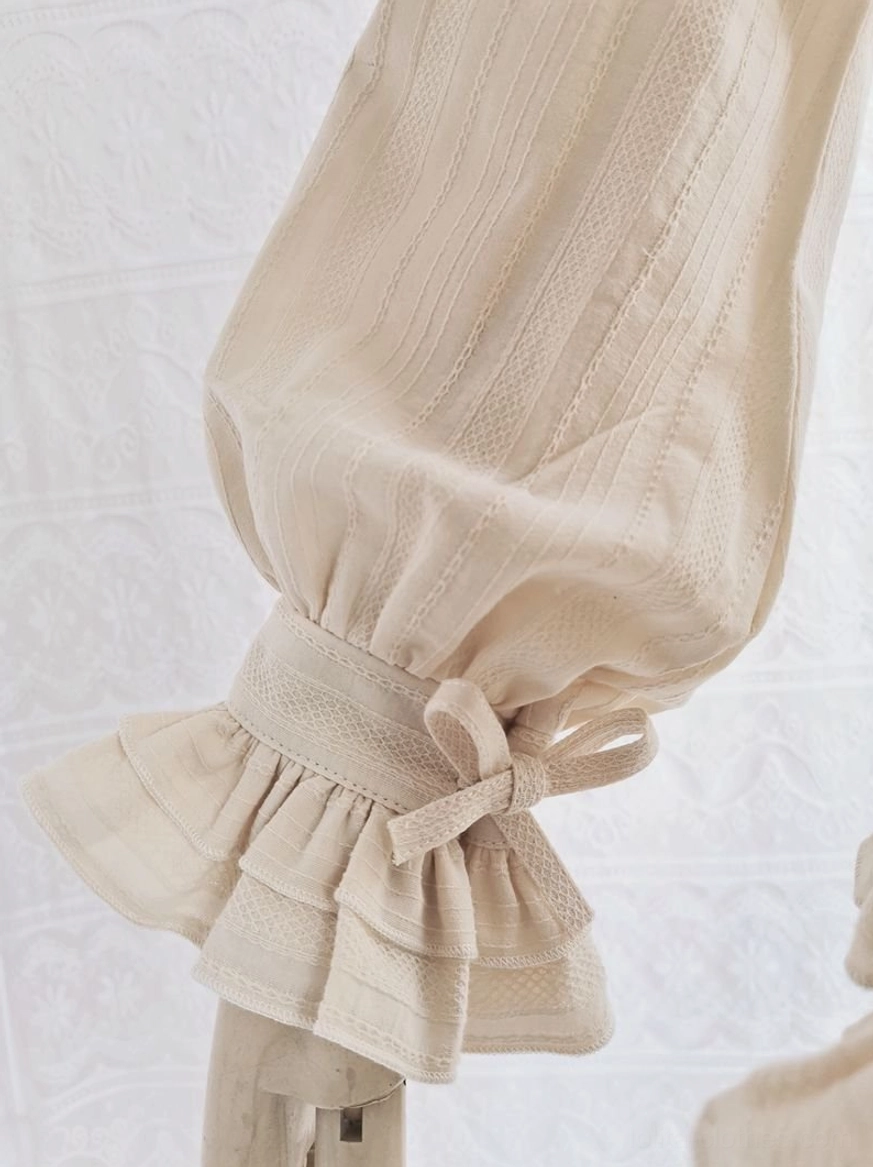 Close-up low angle view beige cotton Lolita blouse ruffled cuff sleeve detail matching fabric bow tie subtle vertical stripe texture woven detail