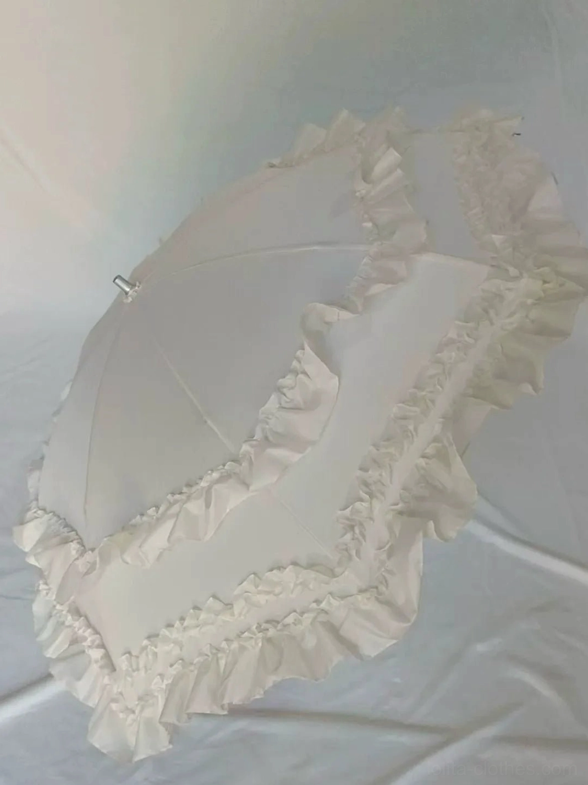 Beige solid colored foldable Lolita parasol with full ruffled edge trims and elegant simplified silhouette, front hanging display on wall hooks without decorative elements