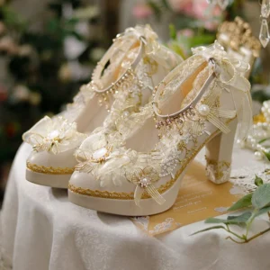 Handcrafted beige and gold pointed-toe Lolita tea party heels with ornamental lace bow and pearl embellishments displayed on vintage lace tablecloth