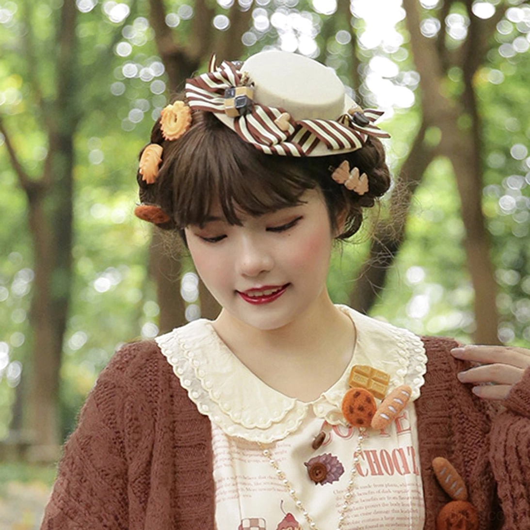 Lolita model wearing beige hand-made chocolate daily sweet lolita flat-top hat with striped bow and biscuit ornament charms in outdoor forest background, complete daily wear coordinate showcase
