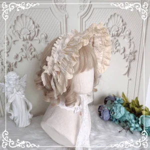 Beige ivory Lolita bonnet headdress with soft ruffled lace edging and matching long lace neck strap, shown in side profile view on classical vintage carved wall backdrop