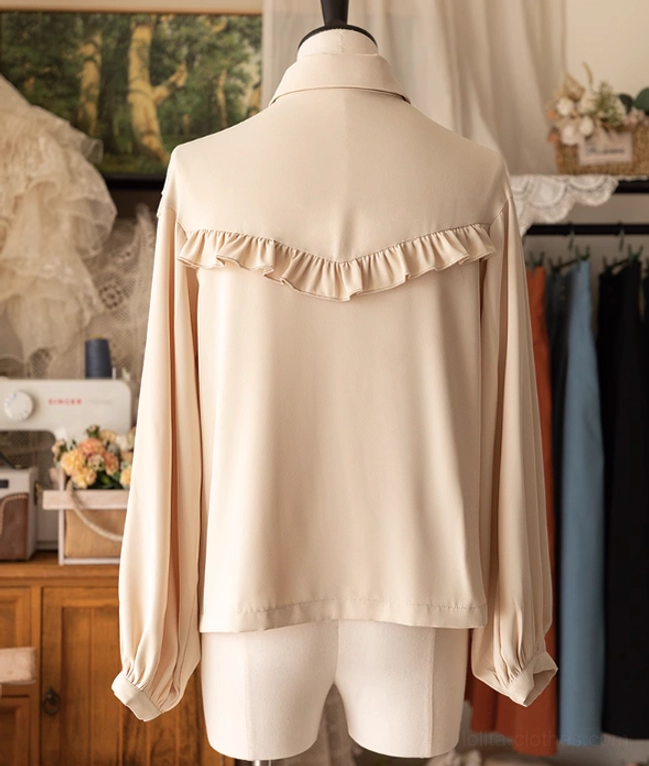 Vintage beige Lolita blouse back view on dress mannequin showing ruffled back yoke decoration and loose long lantern sleeves with plain neutral coloring in retro boutique clothing studio