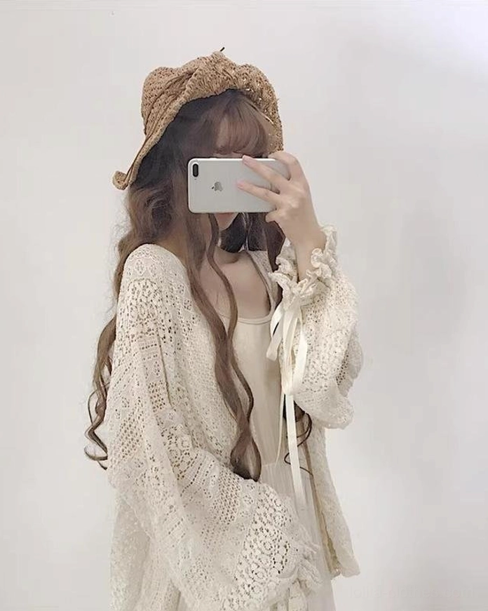 Three-quarter right side view of beige oversized lolita crochet cardigan showcasing hollow knit texture and loose fit silhouette with ribbon sleeve decoration