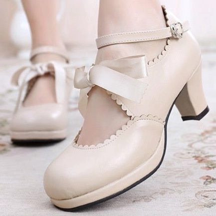 Beige nude handmade lolita high heel shoes with large satin ribbon bow decoration, scalloped collar, ankle buckle strap, and smooth matte leather finish displayed in side close-up view