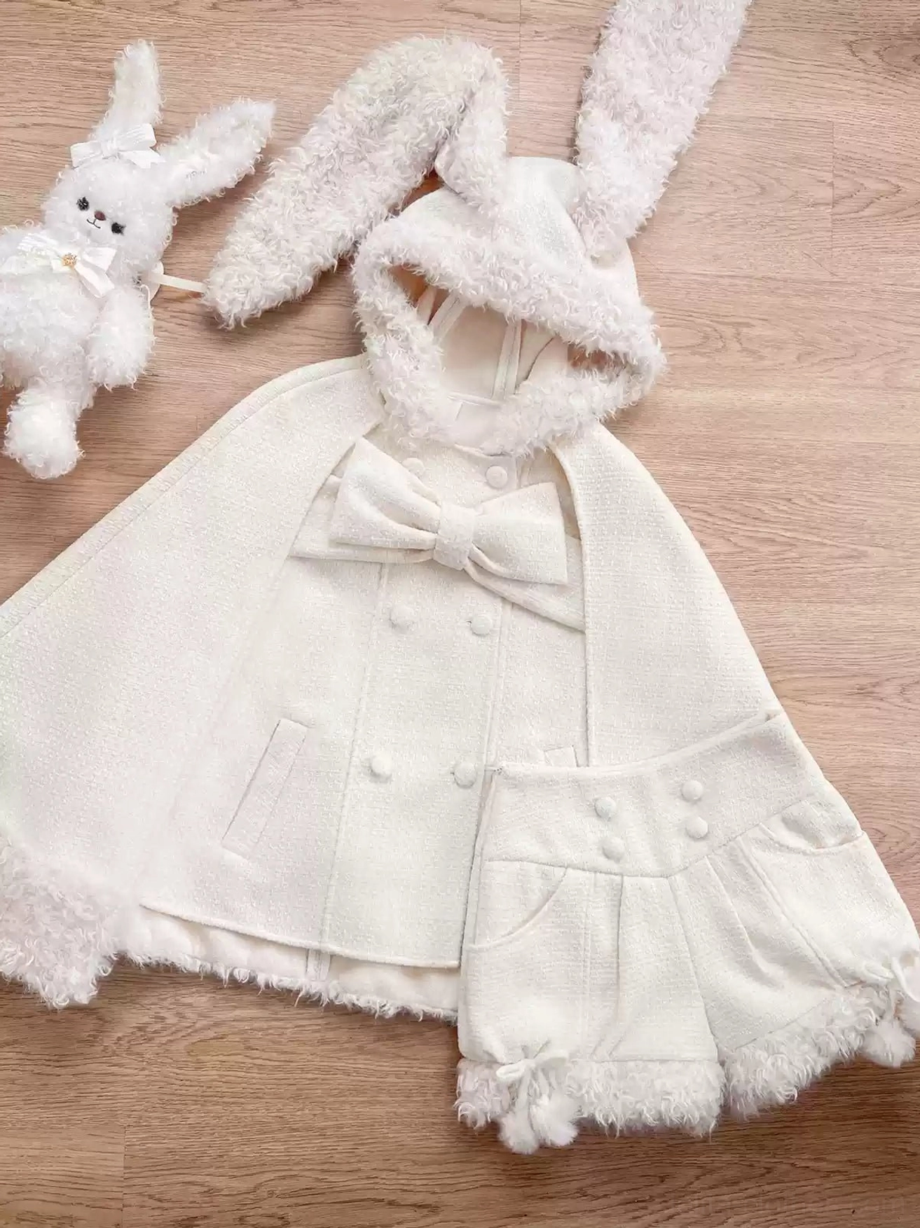 Beige rabbit ear hooded lolita cape isolated product shot showing complete structure hood ears detachable bow side pockets and fluffy tail in studio lighting