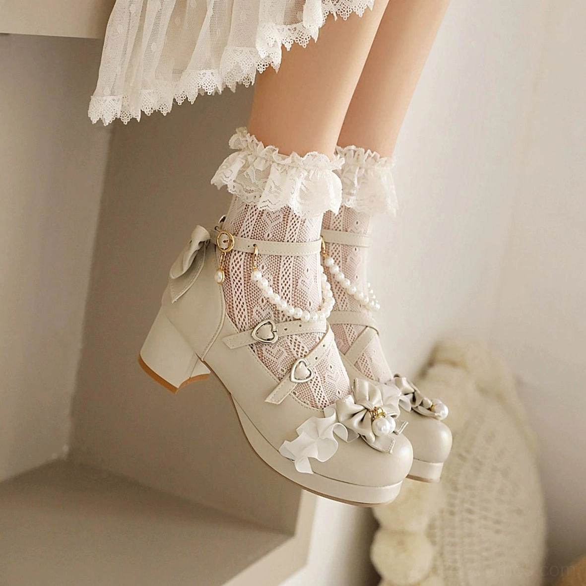 Beige round-toe sweet lolita high heel shoes side profile showing complete detachable pearl ankle chain, matching bow and ruffle decoration on toe, block heel design, modeled with ruffled lace socks and white lace-trimmed skirt