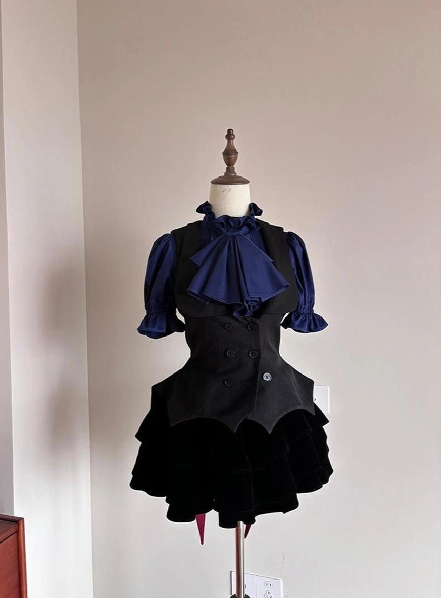 Complete Gothic Lolita outfit styling featuring black bat-wing vest layered over navy blue ruffled short-sleeve blouse with bow tie and ruffled velvet mini skirt