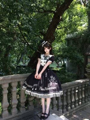 Black Birdsong Symphony lolita OP dress full-body front view on model outdoors showing white ruffled Peter Pan collar musical note print and striped hem details