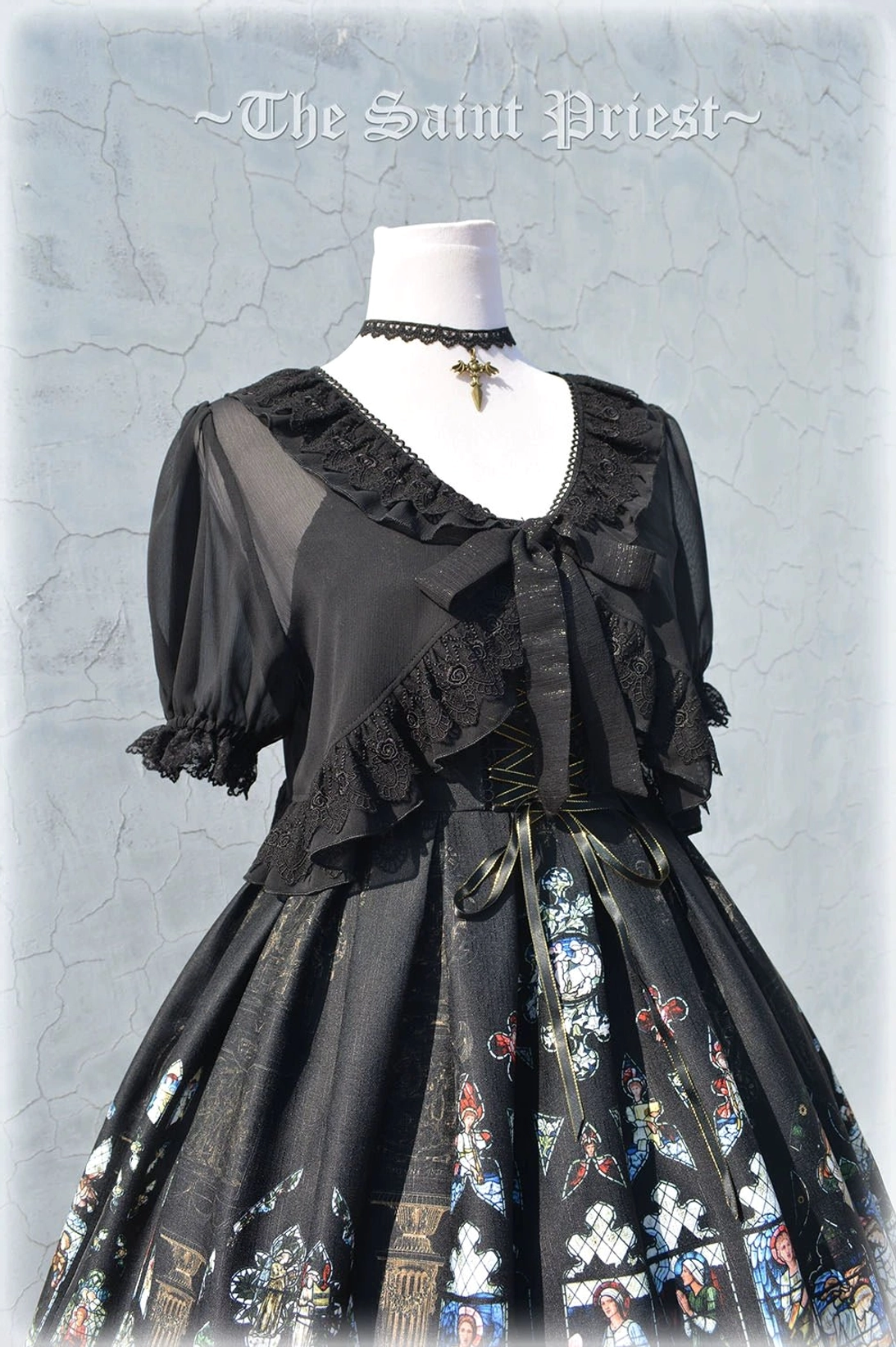 Black with Blue Saint Priest Lolita JSK variant displayed from front, showing ecclesiastical stained glass print, cross-strap design, and blue-toned lace hem trim