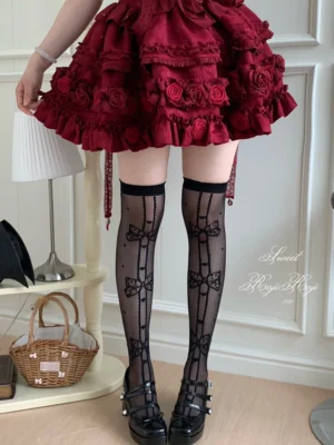 Black sweet lolita thigh-high socks with vertical bow and polka dot embroidery paired with red rose lolita skirt and black buckle mary jane shoes lower body front partial view showcasing sheer glossy fabric and lace top trim