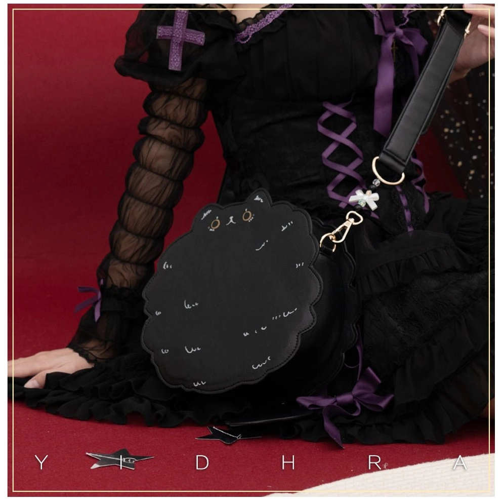 Black kawaii cat leather shoulder bag close-up front view worn with gothic black lolita dress, highlighting hardware details and embroidery on red studio backdrop