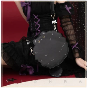 Black kawaii cat leather shoulder bag worn with gothic lolita black dress and red studio backdrop, showcasing side profile with scalloped silhouette and gold hardware details