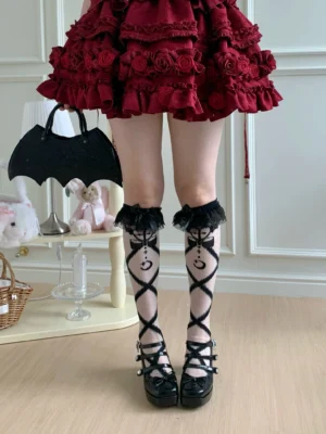 Black crisscross knee-high lolita socks with moon motif details and ruffled lace cuff, matched with red ruffled skirt and black platform shoes