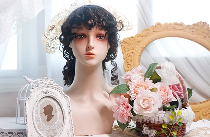 Black curly short bob lolita wig with side curls and gold-trimmed vintage lace headdress displayed with antique decor