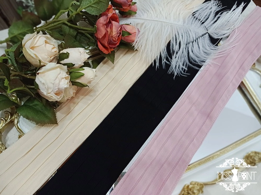 Black and dusty pink satin Lolita waist ties with subtle vertical pleats shown beside red and white roses and a white feather