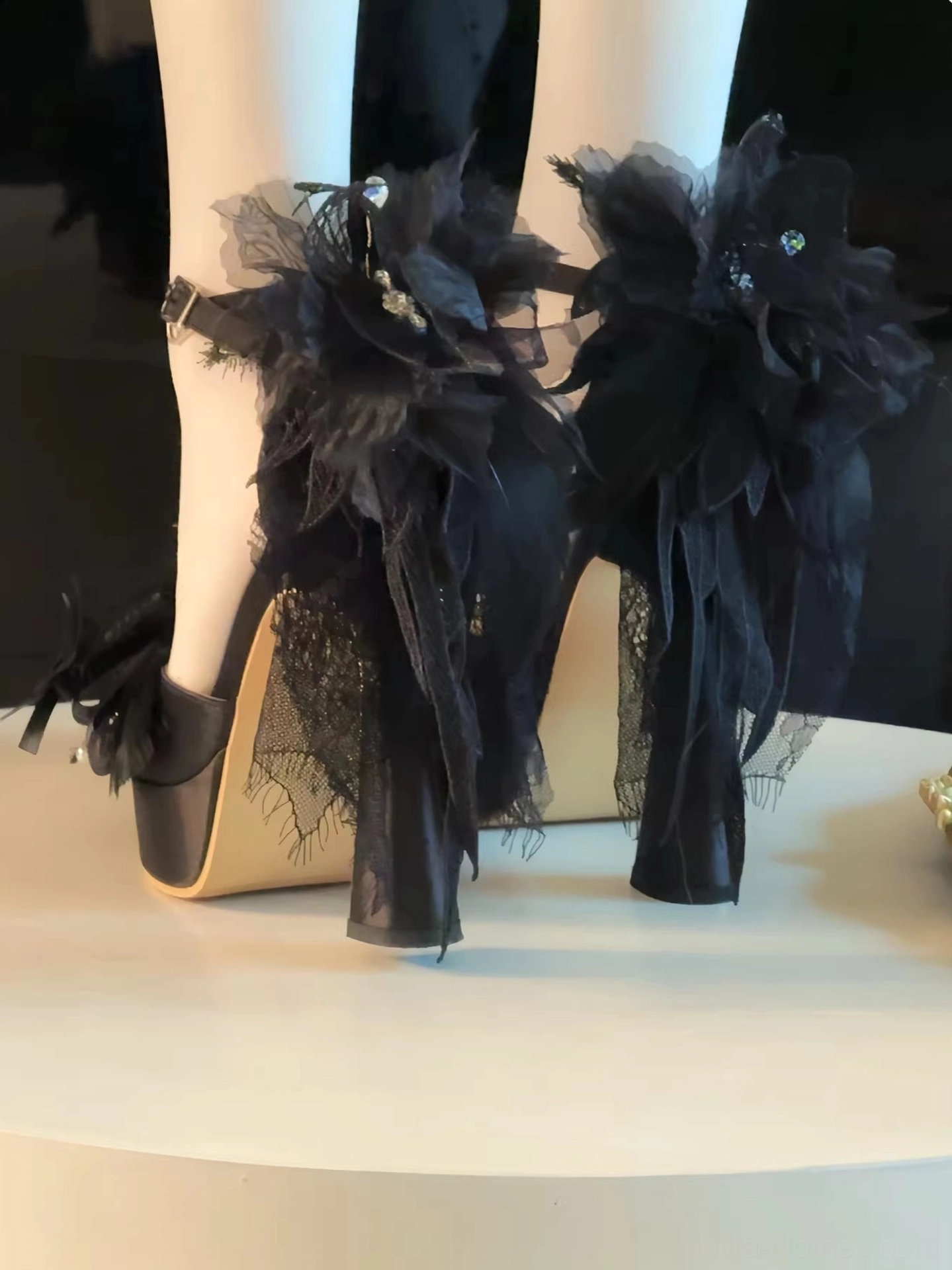 Black exaggerated lolita high heel shoes with oversized black mesh and feather flower decor featuring gem accents, thick block heel, premium satin upper, round display table showcase