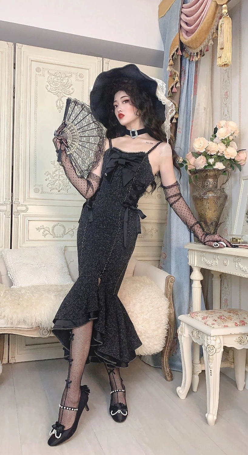 Black fishtail slip Lolita jumper skirt with bust bow decorations, spaghetti straps and ruffled hem, paired with vintage heels and accessories in vanity room setting