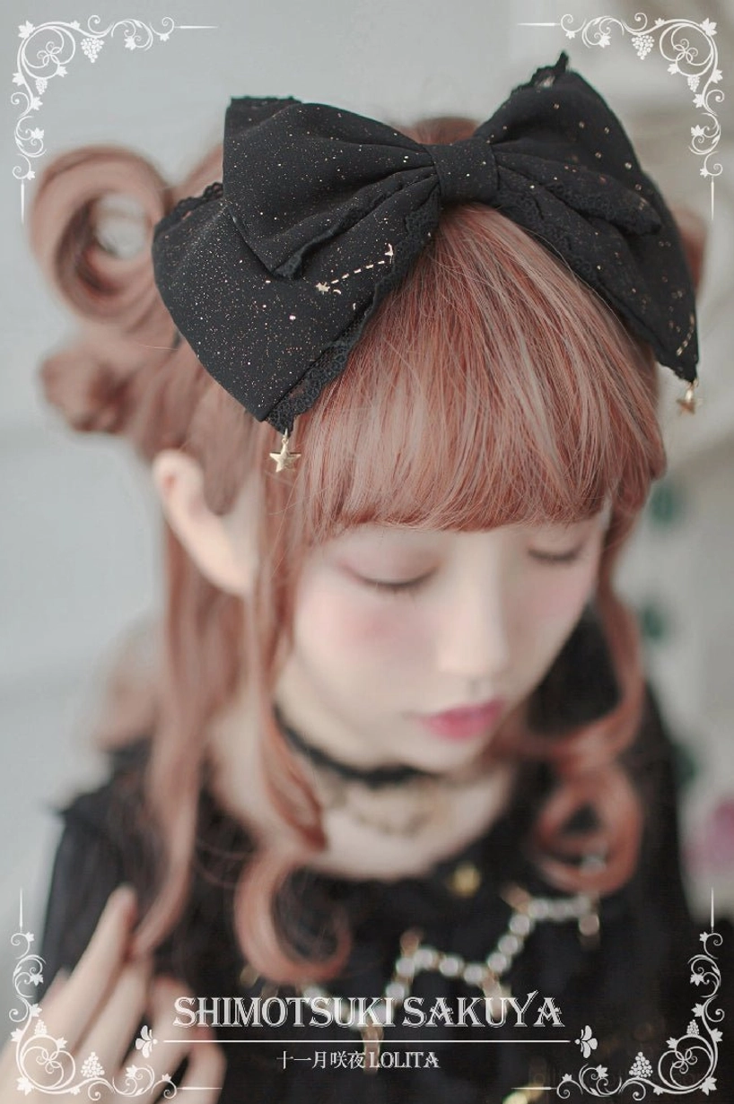 Black glitter Lolita bow headdress with star pendants worn on side of head by model in gothic black Lolita dress close-up portrait
