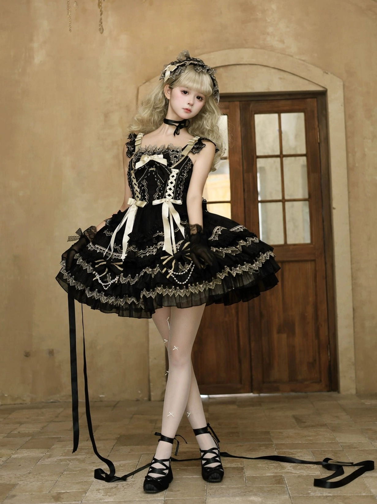 Black and gold gothic lolita jumper dress full body front view with tiered ruffles front ribbon bows detachable long waist straps and black opera gloves