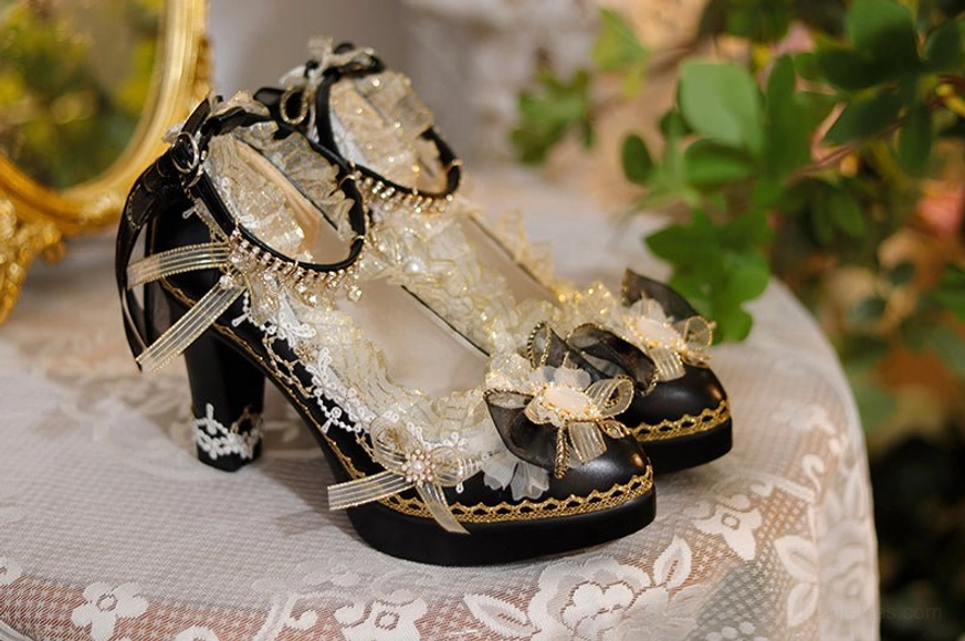 Black and cream luxury pointed-toe Lolita heels with black base gold edging and black bow accents displayed on lace tablecloth