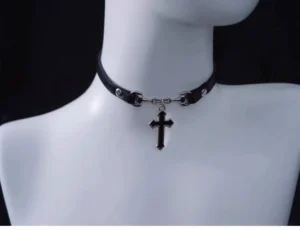 Gothic Lolita cross choker necklace displayed on white mannequin upper body, black leather strap with silver rivets and clasp, enamel cross pendant centered at throat, front medium close-up angle