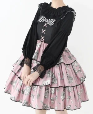 Black gothic-style Lolita blouse with crisscross strap details and contrast ruffled neckline styled with pink tiered printed Lolita skirt