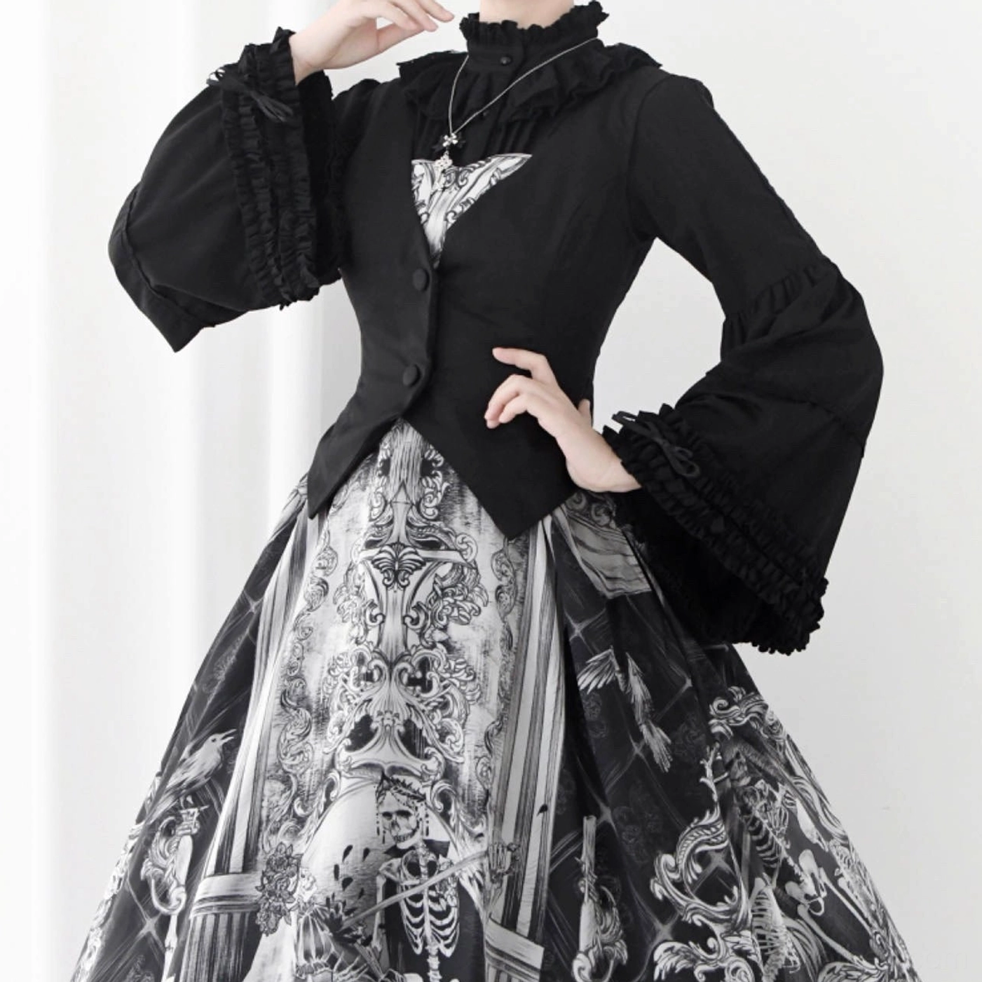 Black gothic Lolita blouse worn with printed skeleton and architecture-themed jumperskirt, three-quarter pose showing ruffled high neck, fitted waist cut, and bell sleeves with ruffled trim