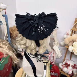 Rear view of black gothic lolita bonnet hat with spider brooch bow and embroidered lace edge, top-down display on wig stand