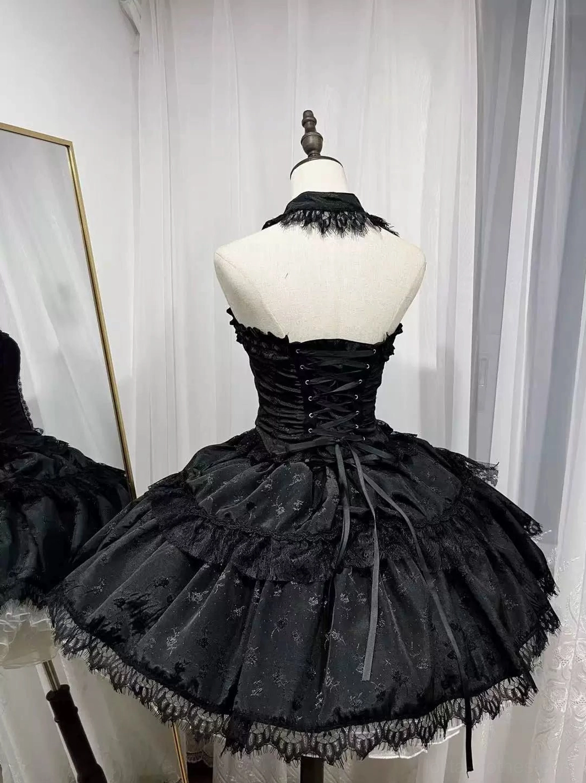 Black gothic lolita corset and mesh skirt set back full view showing lace-up closure and layered ruffled lace-trimmed skirt with cross charms, studio mannequin with mirror background