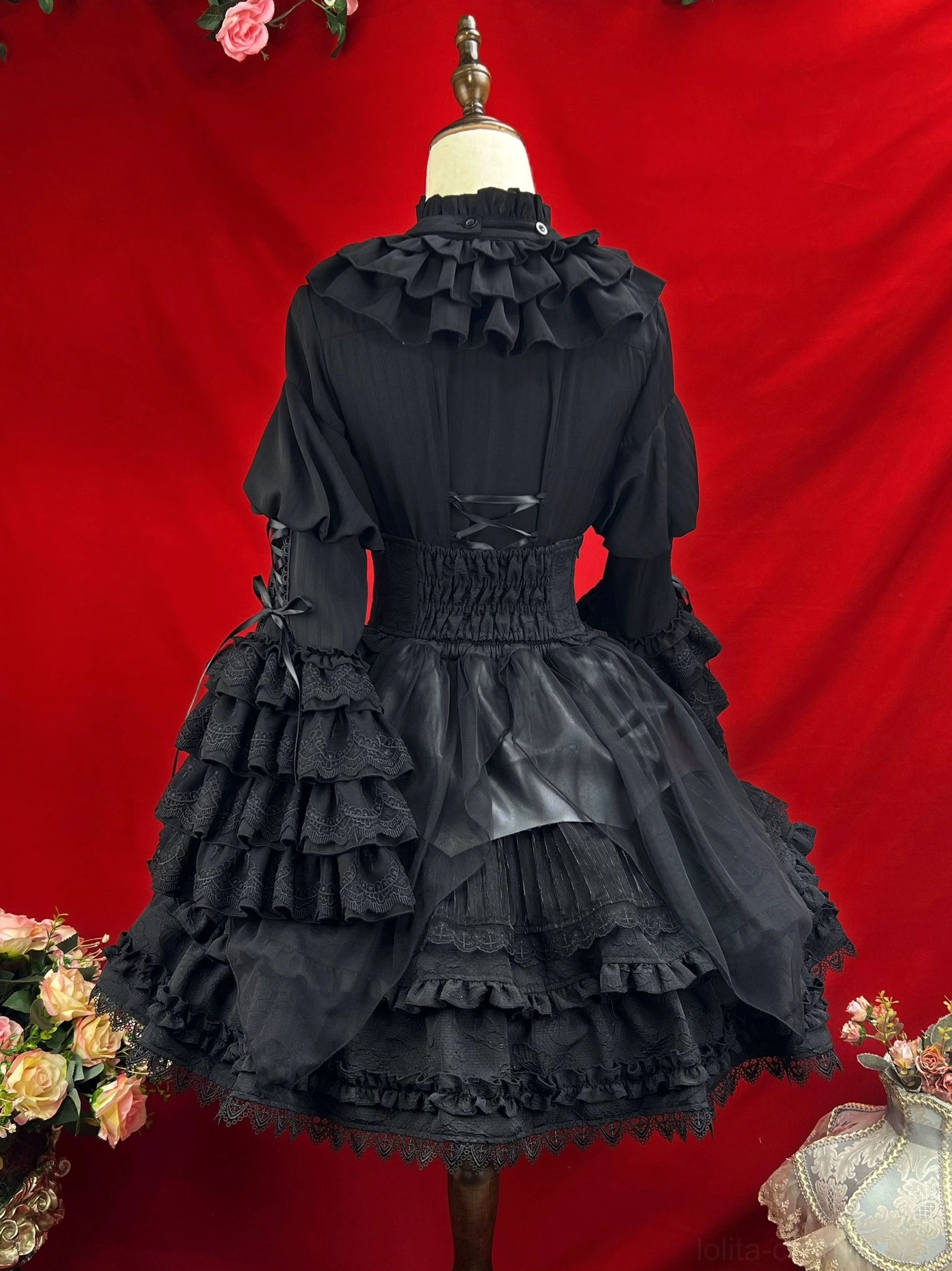 Back view of black gothic lolita dress on mannequin displaying lace-up corset back design ruffled shoulder collar and layered ruffled sleeve construction details