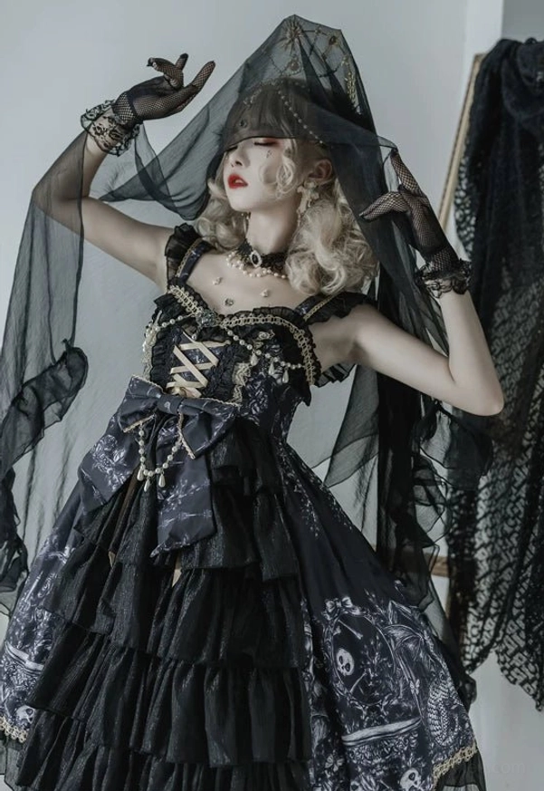Black Gothic Lolita JSK Dress dramatic three-quarter front view with black veil headdress, crisscross lace-up bodice, large waist bow, and dark vintage printed patterns