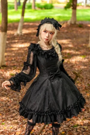 Black gothic lolita JSK dress with jacquard pattern and matching black hairpiece, full front view on model in autumn forest setting with ruffled neckline and semi-sheer long sleeves