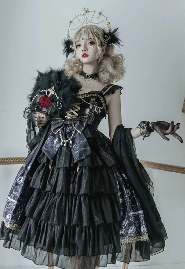 Black Gothic Lolita JSK Dress front three-quarter view with tiered ruffled skirt, crisscross lace-up bodice, waist bow accessory, and feather fan styling